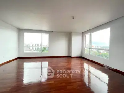 Spacious corner unit with polished hardwood floors and large windows offering city views.