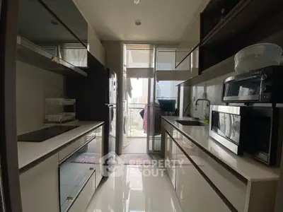 Modern kitchen with sleek appliances and open layout leading to a balcony view.