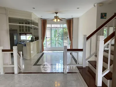 Spacious open-plan living area with elegant staircase and large windows in a modern home.