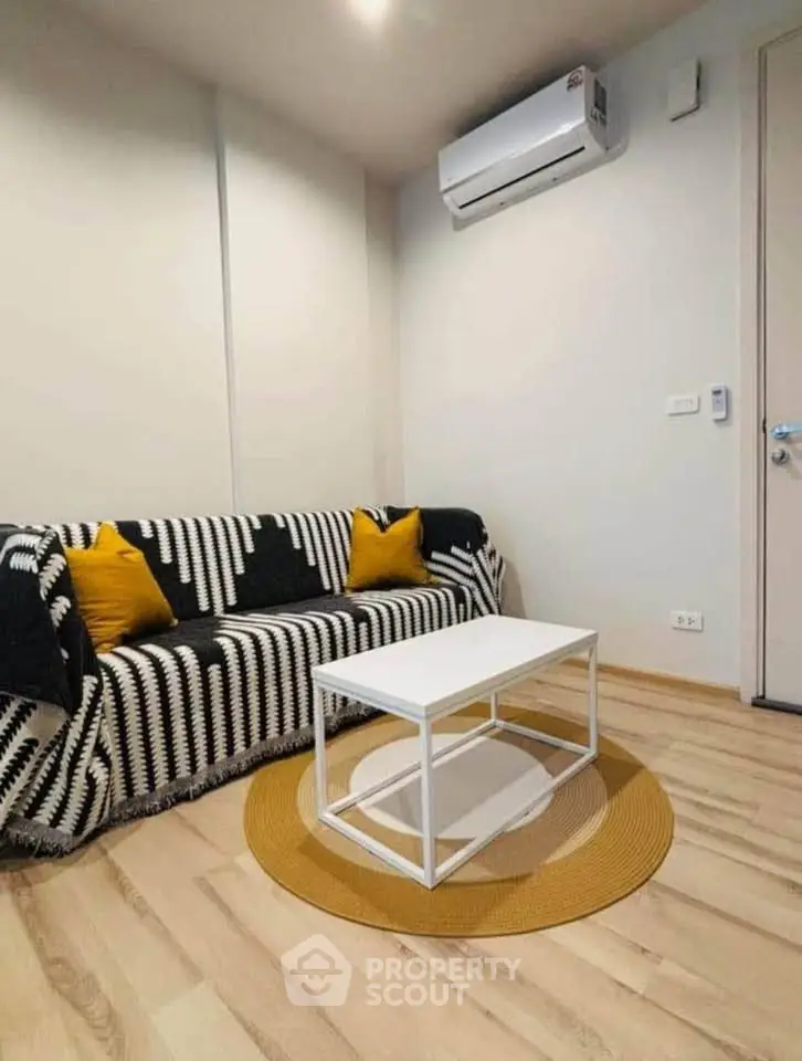 Modern living room with stylish decor and air conditioning, featuring a cozy sofa and sleek coffee table.