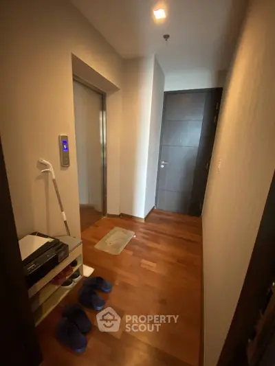 Modern apartment entrance with wooden flooring and elevator access