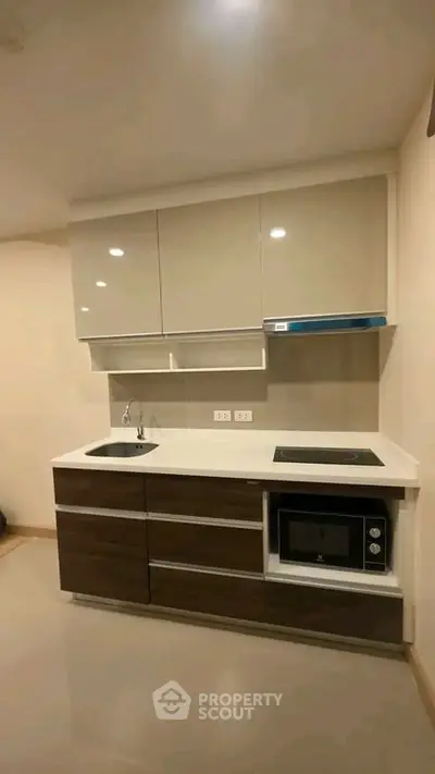 Modern compact kitchen with sleek cabinetry and built-in appliances in a stylish apartment.