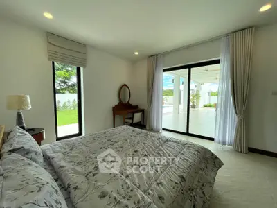 Spacious bedroom with large windows and garden view in modern home