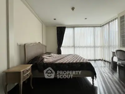 Spacious bedroom with elegant decor and large windows for natural light.