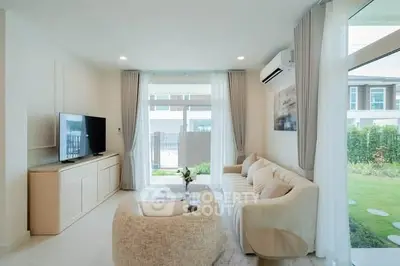 Modern living room with elegant furniture and large windows overlooking a garden, perfect for relaxation.