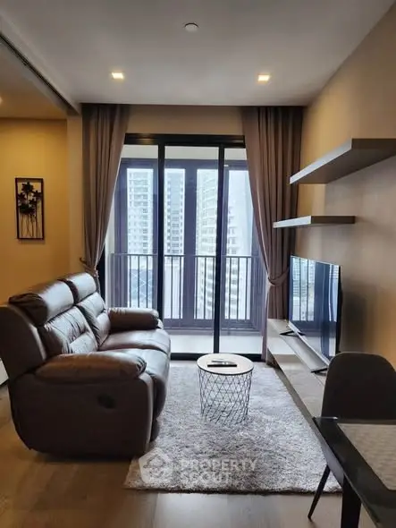 Modern living room with cozy seating and city view balcony in high-rise apartment.