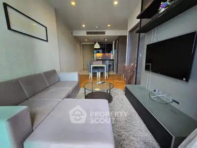 Spacious modern living room with sleek furniture and open layout leading to dining area.