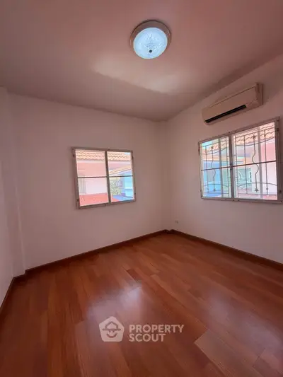 Spacious empty room with wooden flooring and air conditioning, perfect for customization.