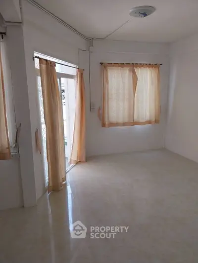 Bright empty room with large windows and beige curtains, ideal for customization.
