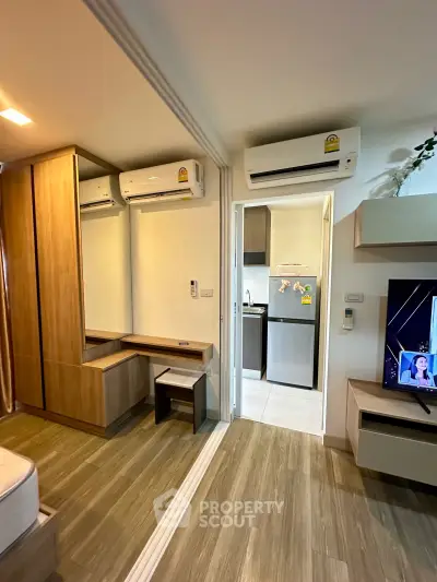 Modern apartment interior with air conditioning and sleek wooden flooring, featuring a compact kitchen and cozy living area.