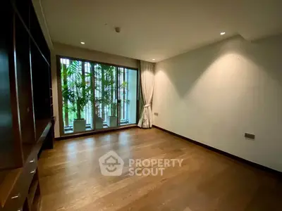 Spacious empty room with large window and wooden flooring, ideal for customization.