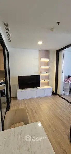 Modern living room with sleek TV stand and open layout, featuring wooden flooring and stylish shelving.