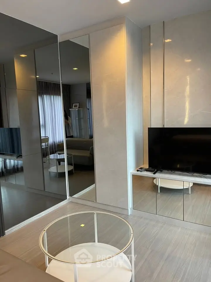 Modern living room with sleek design, featuring a flat-screen TV and stylish glass coffee table.