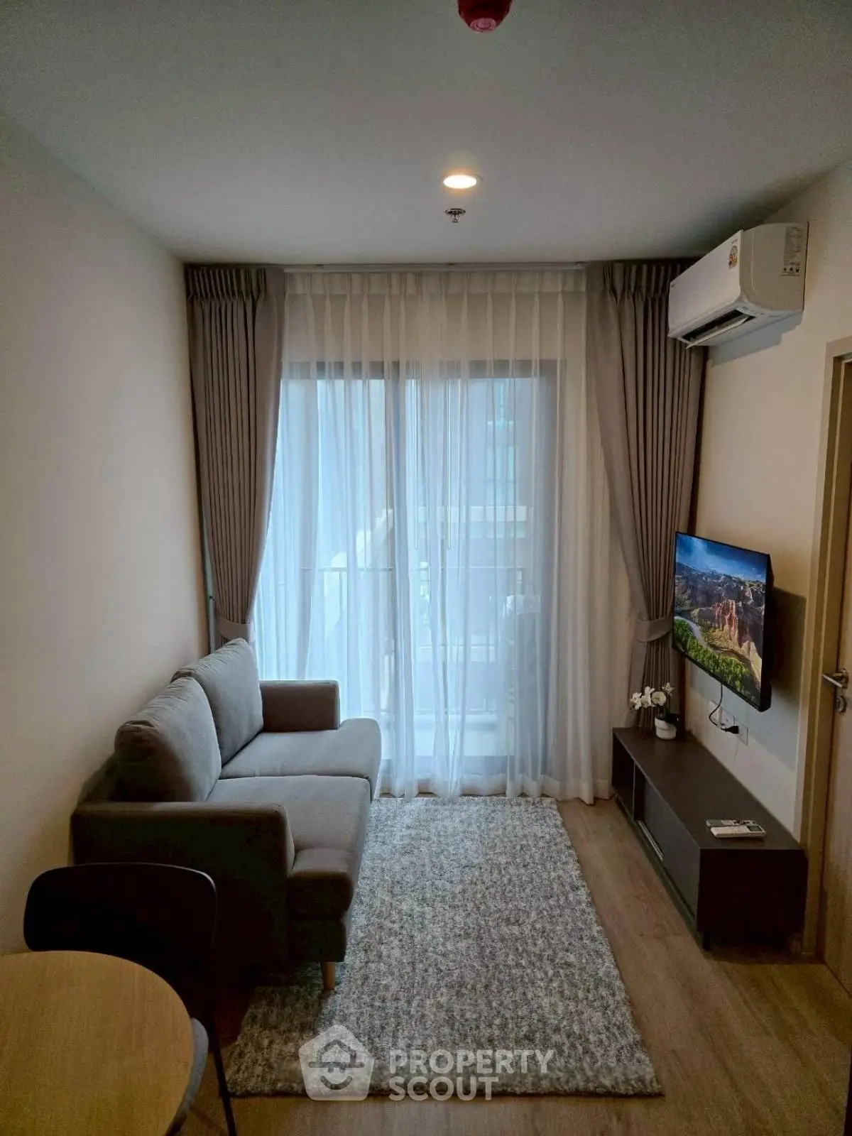 Cozy modern living room with gray sofa, TV, and balcony view