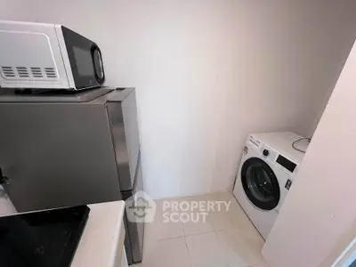 Compact utility room with modern appliances including washing machine, fridge, and microwave.
