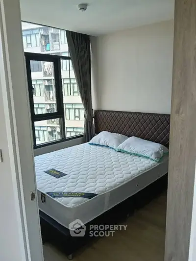 Modern bedroom with large window and stylish headboard in urban apartment