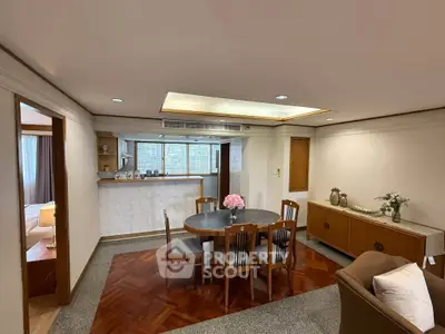 Spacious living room with elegant dining area and open kitchen layout, featuring wooden flooring and modern decor.