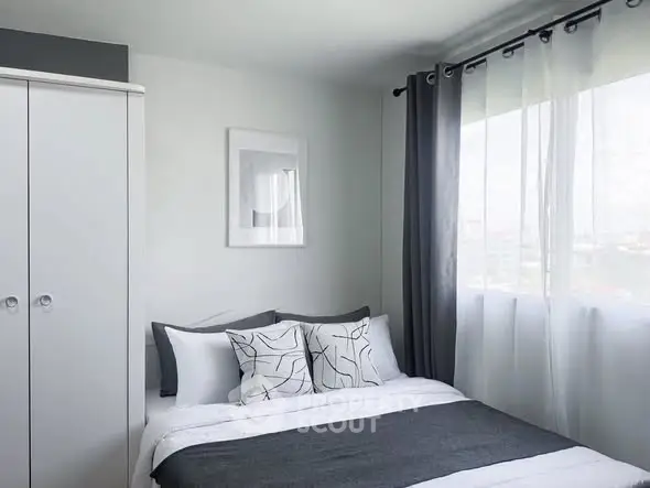 Modern bedroom with stylish decor and large window offering natural light.