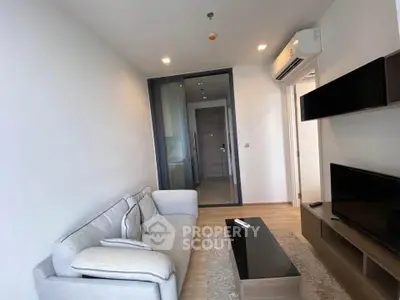 Modern living room with sleek design, featuring a cozy sofa, wall-mounted TV, and air conditioning.