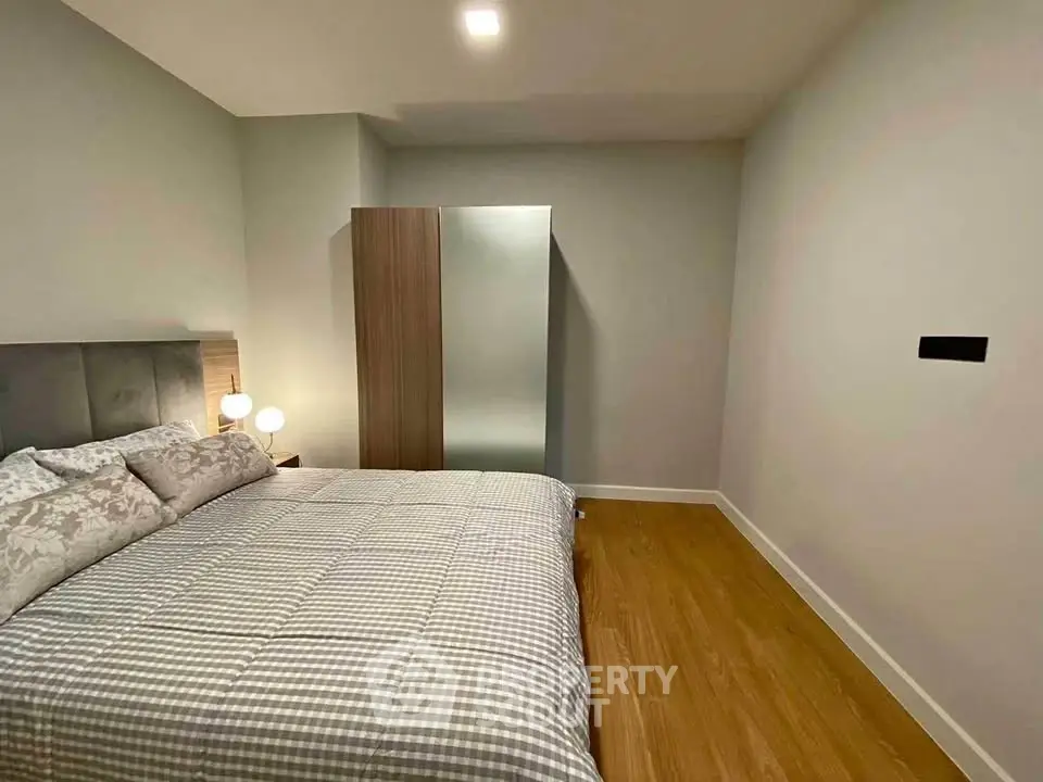 Modern bedroom with cozy bedding and sleek wardrobe in minimalist design.