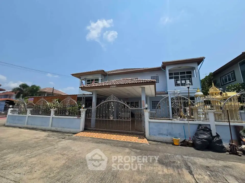 Charming two-story house with gated entrance and spacious front yard in a serene neighborhood.