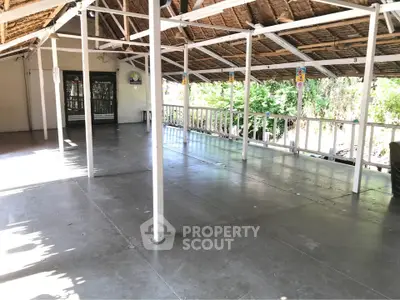 Spacious open-air terrace with rustic wooden roof and natural surroundings, perfect for relaxation or events.