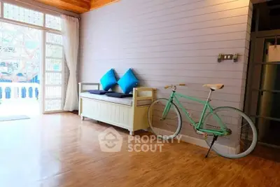 Charming interior with wooden floors, cozy seating, and vintage bicycle in a bright, airy space.
