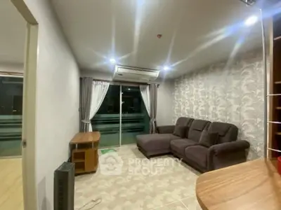 Spacious living room with modern decor and large sofa, featuring a balcony view.