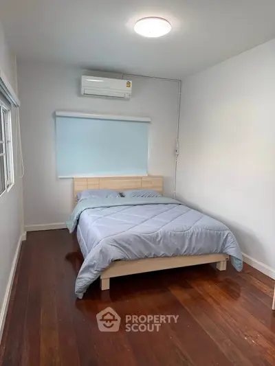 Cozy bedroom with wooden floors and air conditioning, perfect for a comfortable living experience.