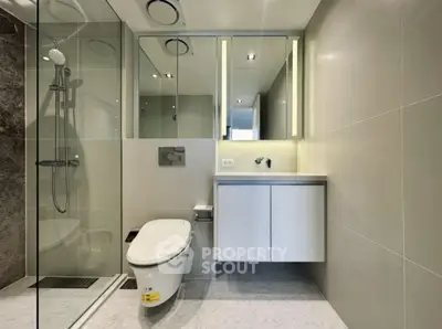 Modern bathroom with sleek design, glass shower, and wall-mounted toilet in luxury apartment.