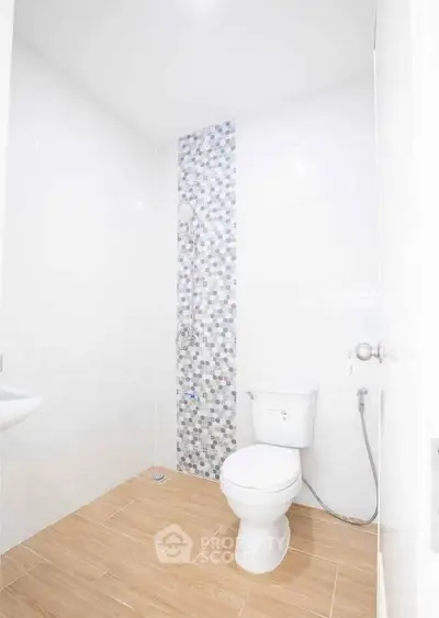 Modern minimalist bathroom with stylish tile accent and wooden floor.
