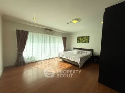 Spacious bedroom with large window and wooden flooring