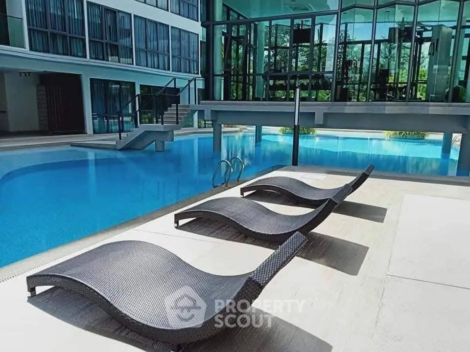 Luxurious poolside area with modern lounge chairs and glass building facade.
