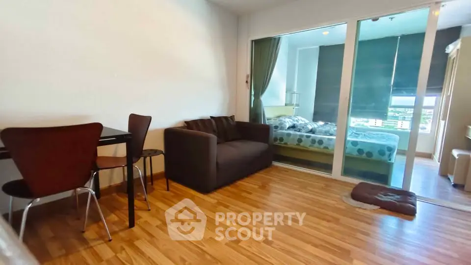 Modern apartment with cozy living room and bedroom, featuring wooden flooring and stylish furniture.