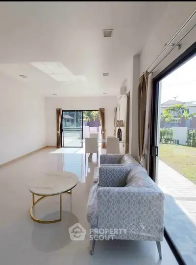 Spacious modern living room with elegant furniture and large windows overlooking a serene garden.