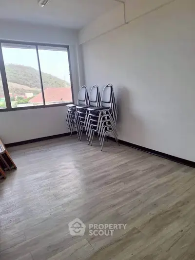 Spacious room with large window and stackable chairs, ideal for versatile use.