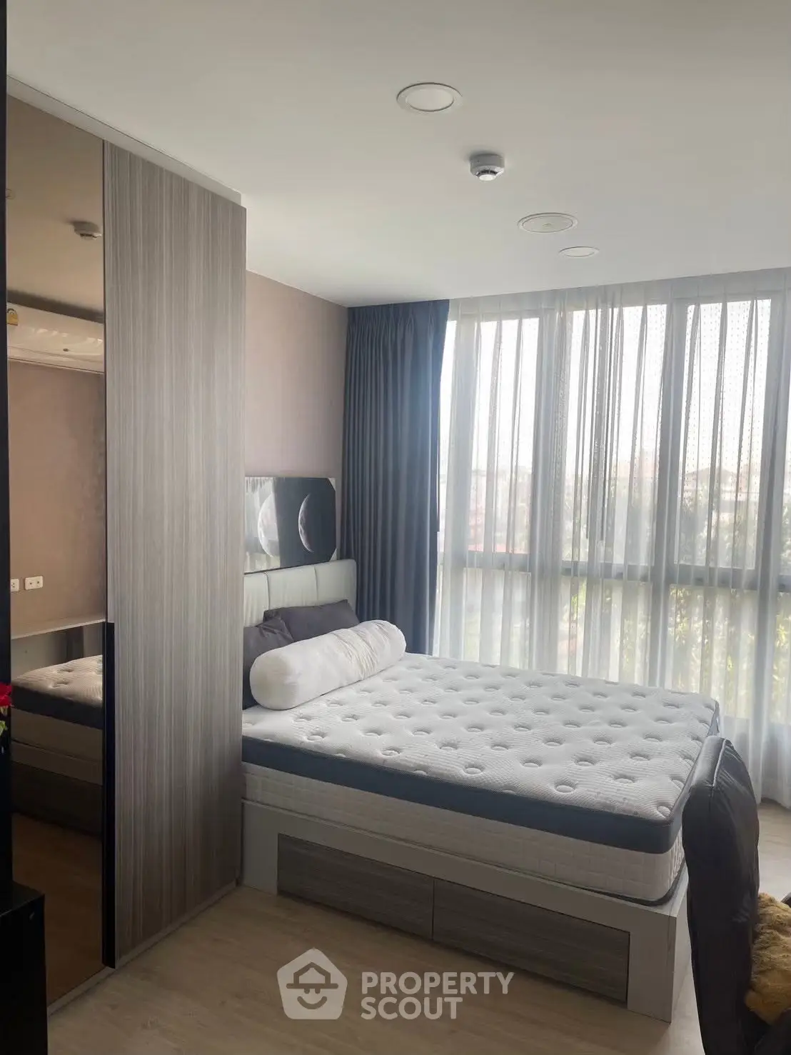 Modern bedroom with large window and stylish decor, featuring a comfortable bed and sleek wardrobe.