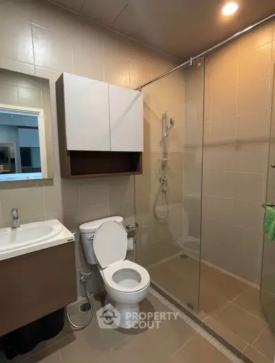 Modern bathroom with glass shower and sleek fixtures in contemporary apartment.
