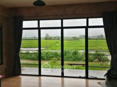 Spacious living room with large windows offering stunning green field views.
