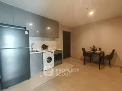 Modern kitchen with sleek cabinets, fridge, and washing machine in cozy apartment.