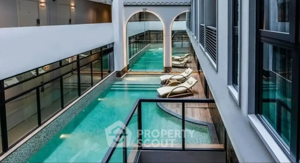 Luxurious indoor pool area with modern design and elegant lounge chairs in a high-end residential building.