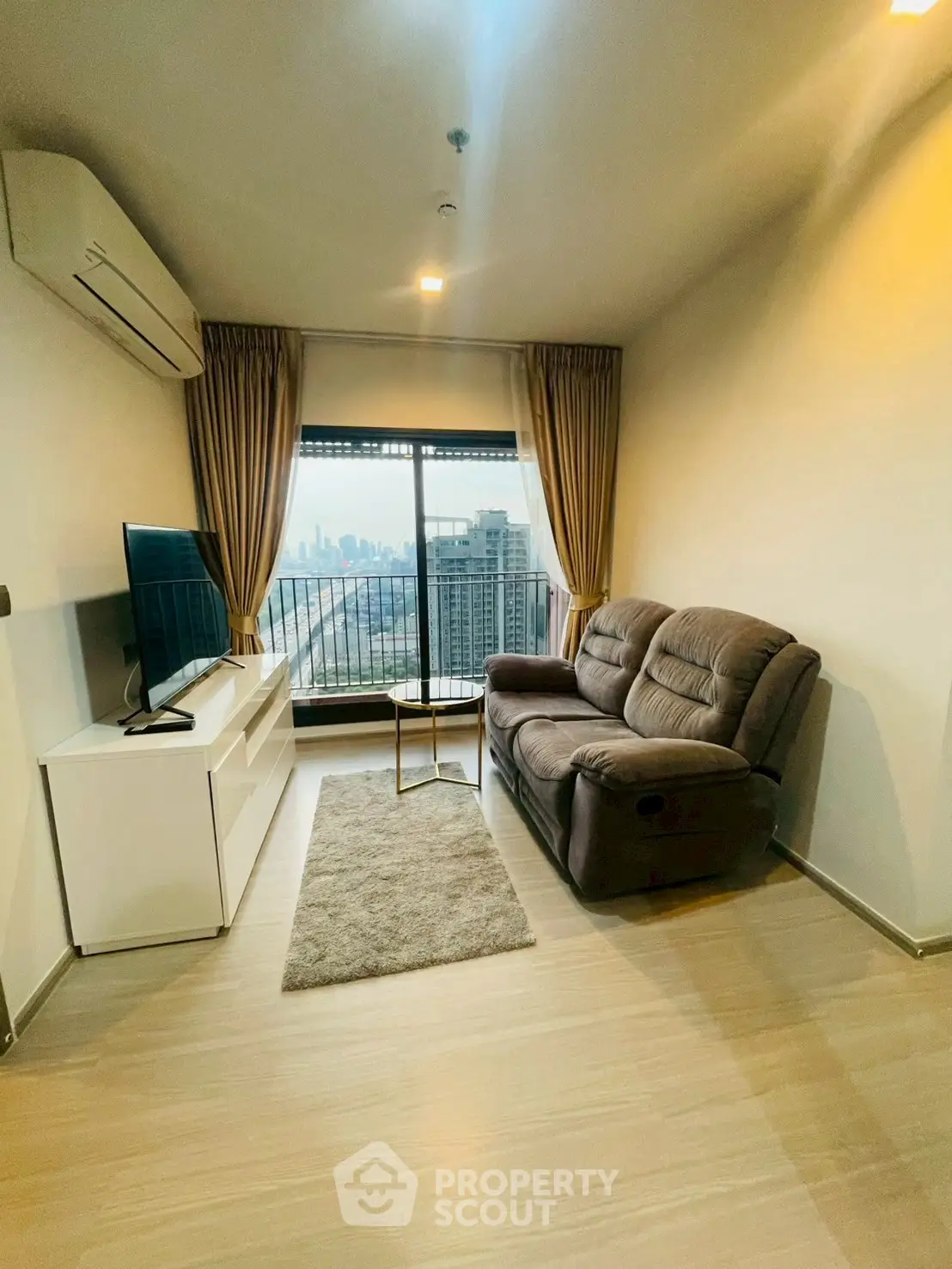 Modern living room with city view, cozy sofa, and sleek entertainment setup.