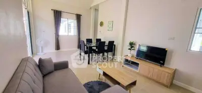 Modern living room with cozy sofa, dining area, and TV setup in bright, airy space.