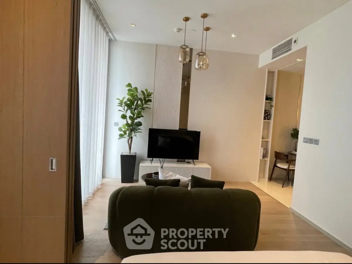Modern living room with stylish decor and natural light, featuring a cozy sofa and sleek TV setup.