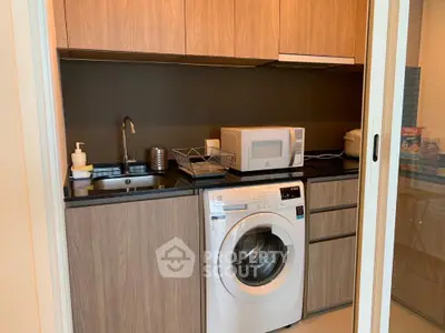 Modern kitchen with washing machine and microwave in compact layout