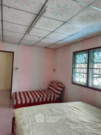 Cozy bedroom with patterned ceiling and window grills, featuring a comfortable bed and chaise lounge.