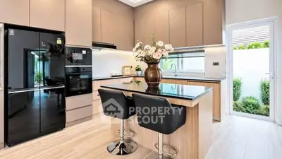 Modern kitchen with sleek cabinets, island seating, and large fridge in a bright, airy space.