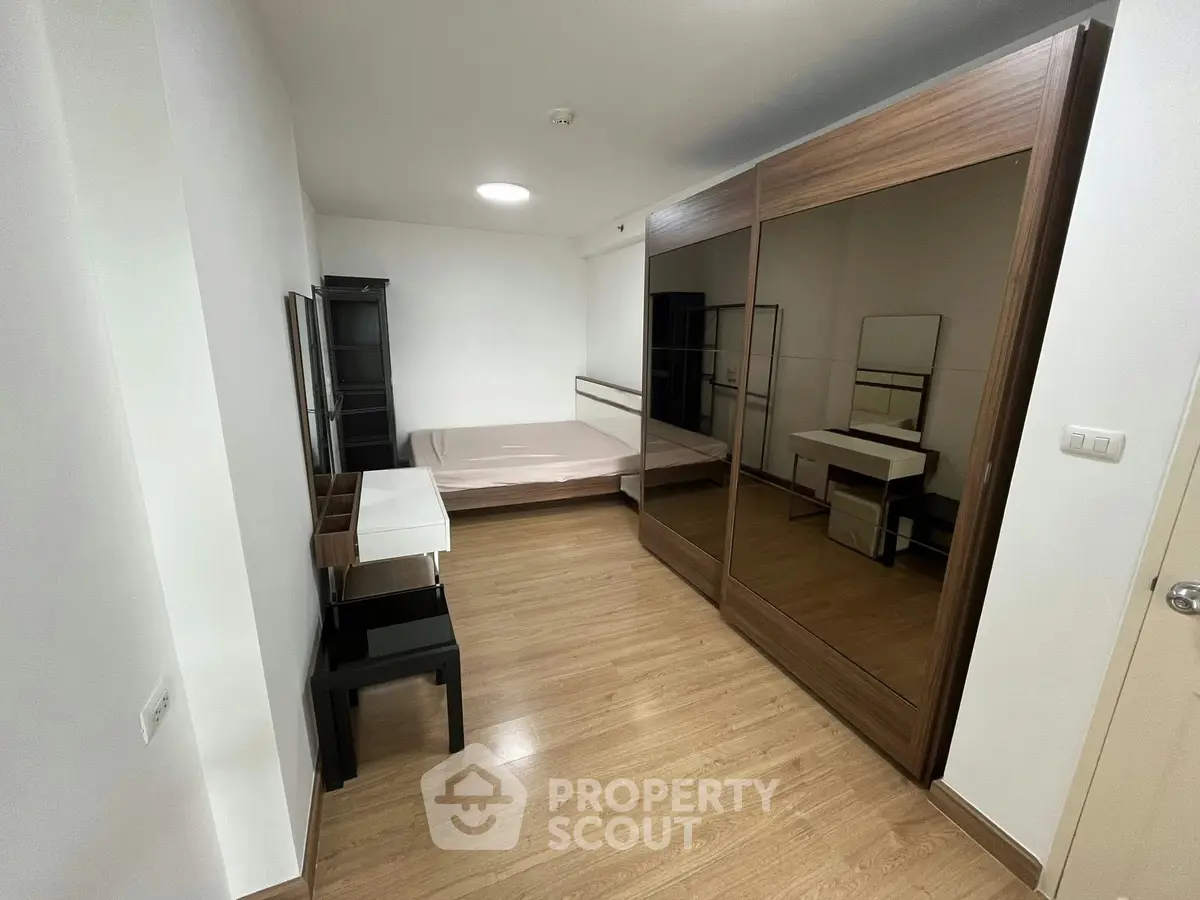 Spacious bedroom with modern mirrored wardrobe and wooden flooring