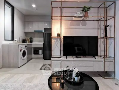 Modern living room with stylish shelving and open kitchen layout featuring washing machine and sleek appliances.