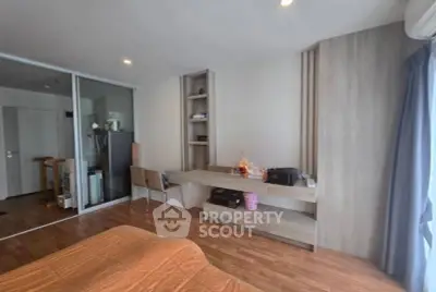 Modern bedroom with wooden flooring and built-in desk, featuring ample natural light.